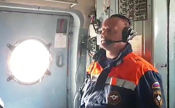 На фото: сотрудник МЧС РФ на борту вертолета Ми-8 во время вылета в поселок Палана для участия в поисках пропавшего самолета Ан-26.