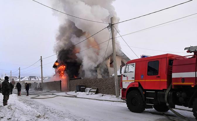 На фото: пожарная машина МЧС РФ у горящего деревянного двухэтажного дома в селе Хомутово, Иркутская область