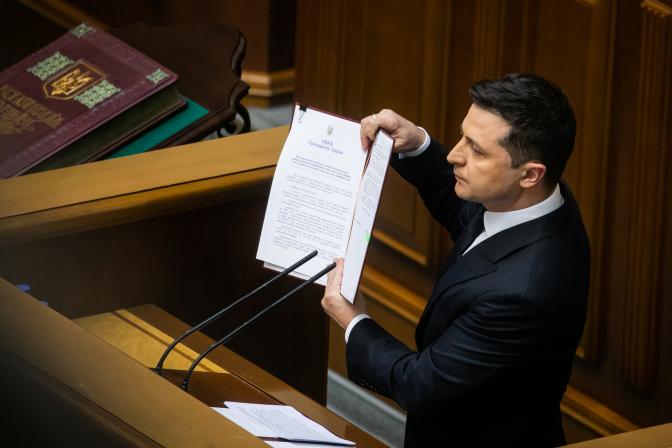 На фото: президент Украины Владимир Зеленский держит в руках указ, который предусматривает укрепление обороноспособности Украины, увеличение зарплаты военных, на седьмой сессии Верховной рады девятого созыва