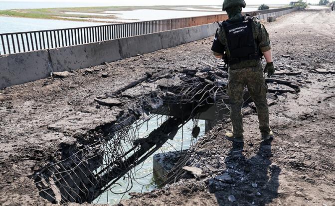 На фото: сотрудник Следственного комитета РФ на поврежденном мосту недалеко от Чонгара