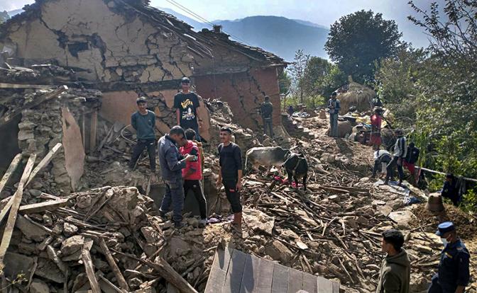 На фото: жители непальской деревни стоят среди обломков своих глинобитных домов после землетрясения в Непале