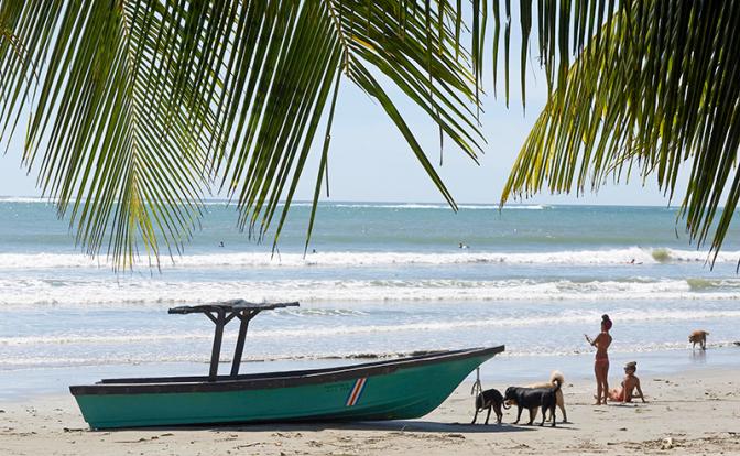 На фото: костариканские женщины и собаки на пляже, Плайя Самара, полуостров Никойя, Коста-Рика, Центральная Америка