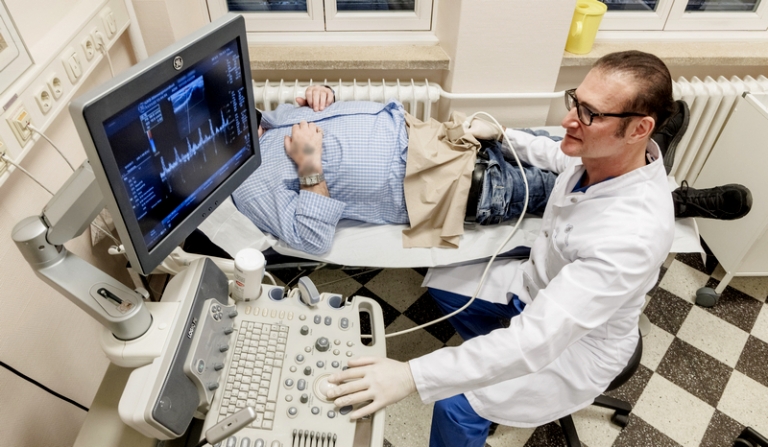 На фото: осмотр пациента с помощью ультразвукового устройства.