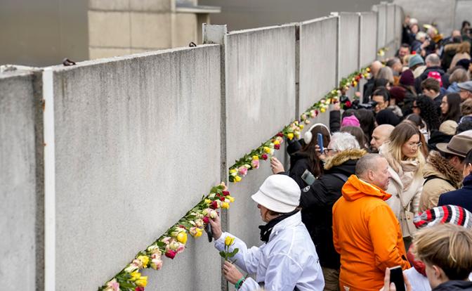 На фото: люди принимают участие в церемонии возложения цветов по случаю 35-й годовщины Берлинской стены на территории Мемориала Берлинской стены, Берлин, Германия.