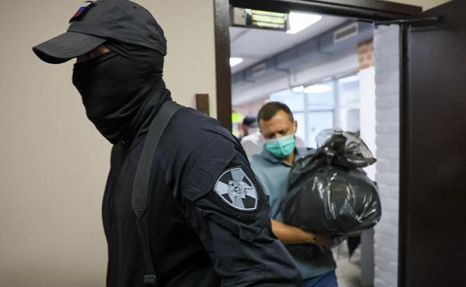 На фото: сотрудники правоохранительных органов выносят документы из редакции телеграм-канала Baza