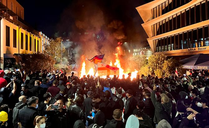 На фото: протестующие у резиденции президента Грузии подожгли навесы и скамейки близлежащих кафе.