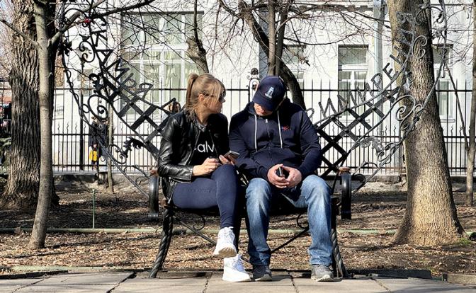 На фото: мужчина и женщина сидят на скамейке с надписью «Скамья примирения».