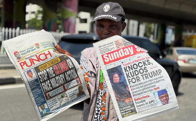 На фото: продавец с газетами в которых упоминаются комментарии президента США Дональда Трампа о Нигерии
