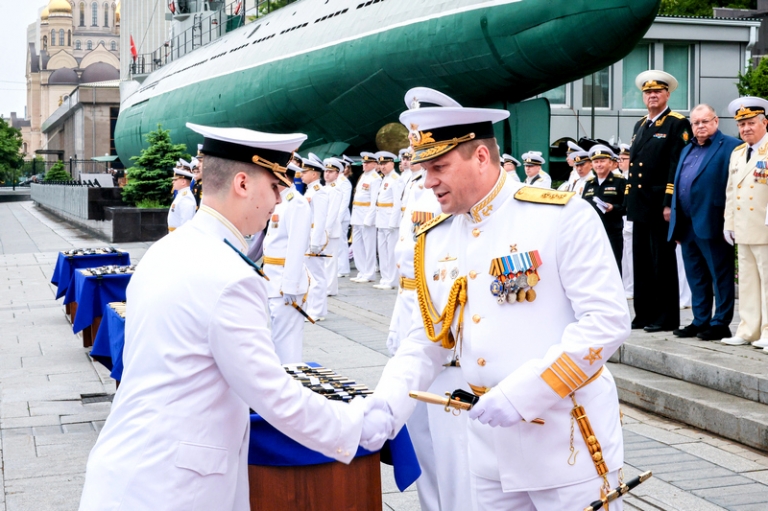 На фото: командующий Тихоокеанским флотом адмирал Виктор Лиина (справа на первом плане) во время вручения морского кортика военнослужащему на 81-й церемонии выпуска офицеров и мичманов Тихоокеанского высшего военно-морского училища (ТОВВМУ) имени С.О. Макарова на Корабельной набережной у мемориала "Боевая слава Тихоокеанского флота", 2024 год.