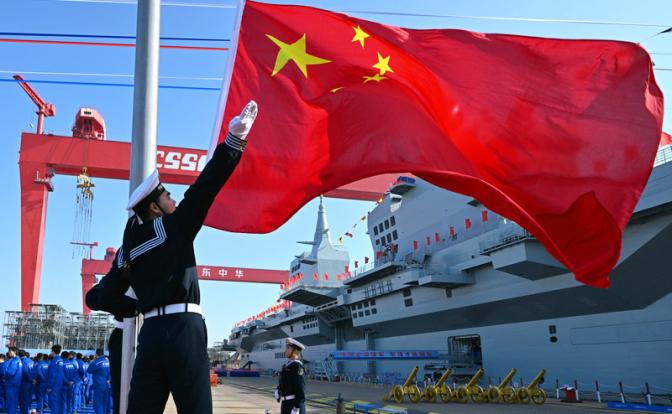 На фото: церемония поднятия флага во время спуска на воду первого китайского десантного корабля нового поколения типа 076, получившего название «Сычуань», на верфи «Худун-Чжунхуа», дочернем предприятии Китайской государственной судостроительной корпорации
