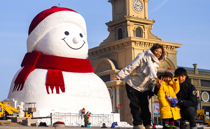 На фото: семья из трех человек позирует перед гигантским снеговиком в музыкальном парке Цюньли в Харбине, провинция Хэйлунцзян, Китай.