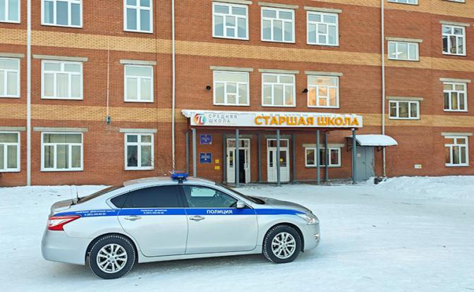 На фото: автомобиль полиции у школы, где восьмиклассница напала на одноклассников и учителя.