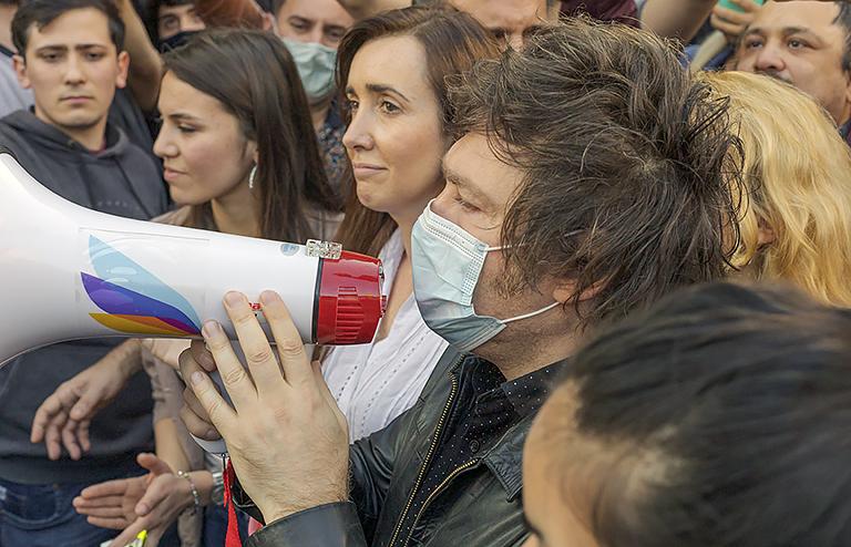 На фото: Хавьер Милей обращается в мегафон к своим последователям в сопровождении кандидата Виктории Вильярруэль, 2021